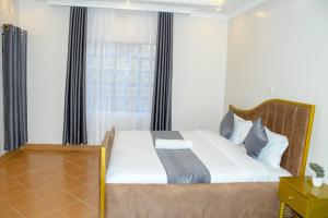 1 dormitorio con 1 cama con sábanas blancas y ventana en Effie Homes en Naivasha