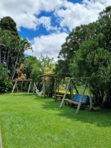 um parque com dois baloiços e uma árvore em Villa Garibaldi em Joanópolis