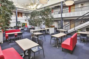 une cafétéria vide avec des tables et des chaises rouges dans l'établissement ACE Hôtel Vendée Saint Hermine, à Sainte-Hermine