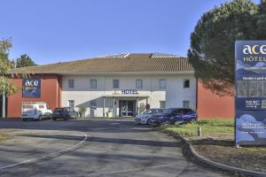 een hotel met auto's geparkeerd op een parkeerplaats bij ACE Hôtel Vendée Saint Hermine in Sainte-Hermine