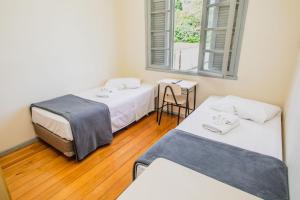 um quarto com duas camas e uma mesa e uma janela em Pousada Convento São Lourenço em Porto Alegre
