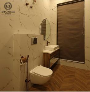 a bathroom with a toilet and a sink and a mirror at Tropical Palms in Gurgaon