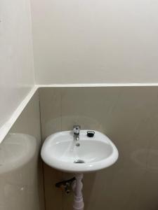 a white sink in a white tiled bathroom at Maria kulafu studio 2 in Masbate