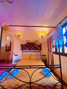 - une chambre avec un lit à baldaquin dans l'établissement Riad le petit jardin, à Zagora