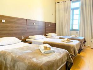 a hotel room with three beds with towels on them at Pousada Convento São Lourenço in Porto Alegre