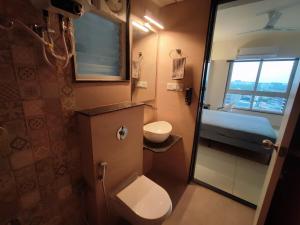 a small bathroom with a toilet and a bed at Beta Room in Ahmedabad