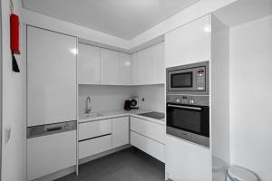 Una cocina blanca con gabinetes blancos y un microondas. en Bessa Luxury Flat by Amber Star Rent, en Oporto