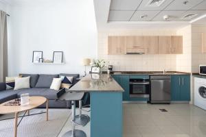 杜拜的住宿－Frank Porter - BayCentral，厨房以及带蓝色沙发的客厅。
