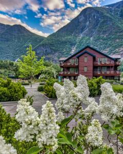 a house with mountains in the background with white flowers at Flåmsbrygga Hotel in Flåm