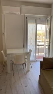 - une table et des chaises blanches dans une chambre avec fenêtre dans l'établissement SoleMare, à Bellaria-Igea Marina