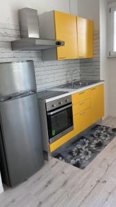 d'une cuisine équipée d'un réfrigérateur en acier inoxydable et de placards jaunes. dans l'établissement SoleMare, à Bellaria-Igea Marina