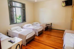 um quarto com três camas e uma janela em Pousada Convento São Lourenço em Porto Alegre