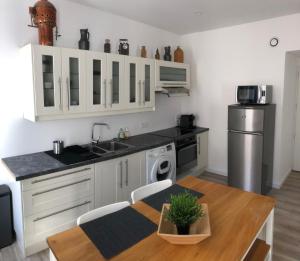 a kitchen with white cabinets and a table and a sink at Joli logement au centre de Trévoux in Trévoux