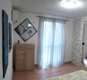 - une chambre avec un rideau blanc et une commode en bois dans l'établissement Casetta Lago di Paola Sabaudia - San Felice Circeo, à SantʼAlfonso