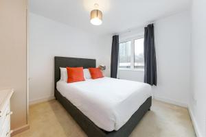 a bedroom with a large white bed with orange pillows at Clerkenwell Serviced Apartments in London