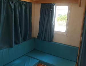 niebieską kanapę w pokoju z oknem w obiekcie Camping Sant Salvador w mieście Comarruga