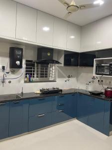 a kitchen with blue and white cabinets and appliances at Vinayaka Villas in Hyderabad