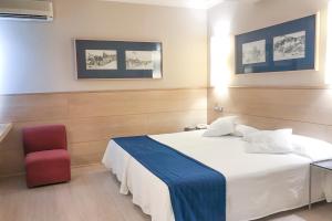 een slaapkamer met een wit bed en een rode stoel bij Hotel Virrey in Arnedo