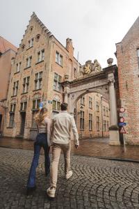 um homem e uma mulher a andar em frente a um edifício em Martin's Brugge em Bruges