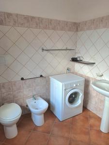 a bathroom with a washing machine and a toilet at Yellon House in Santa Maria Navarrese