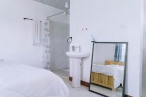 a white bedroom with a sink and a mirror at Ambokili Farm Country House in Kimana