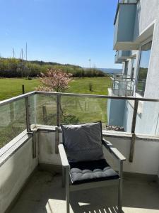 une chaise sur un balcon avec vue sur l'océan dans l'établissement Ferienwohnung Sailing, à Schausende