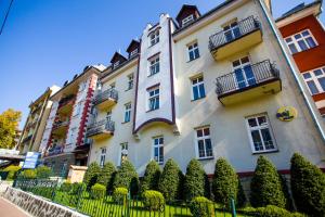 duży biały budynek z krzakami przed nim w obiekcie Hotel *** NAT Krynica Zdrój w mieście Krynica Zdrój