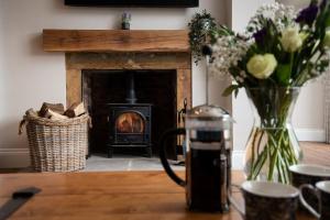 a table with a vase of flowers and a fireplace at Mill Cottage, Brockmill Farm in Berwick-Upon-Tweed