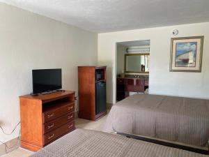 Schlafzimmer mit einem Bett und einer Kommode mit einem TV in der Unterkunft Jasmine Garden Inn - Lake City in Lake City