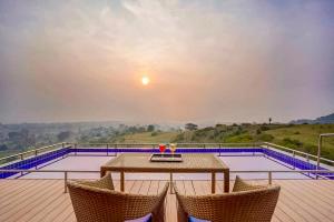 - une table et deux chaises sur une terrasse avec une piscine dans l'établissement Wabi Sabi Resort, Igatpuri, à Igatpuri