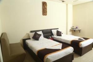 a room with two beds and a chair in it at Park Niveda in Shamshabad