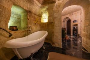 ein Badezimmer mit einer Badewanne in einer Steinwand in der Unterkunft Signature Cave Cappadocia, Trademark Collection by Wyndham in Ürgüp