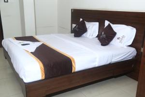 a bed with white sheets and black pillows at Park Niveda in Shamshabad