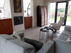 a living room with couches and a tv and windows at Huis met 4 slaapkamers tussen Antwerpen en Brussel in Rumst