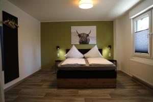 a bedroom with a bed with a picture of a cow on the wall at Hotel Weilerhof in Dormagen