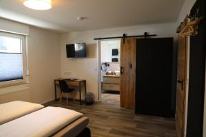 a bedroom with a bed and a desk and a door at Hotel Weilerhof in Dormagen