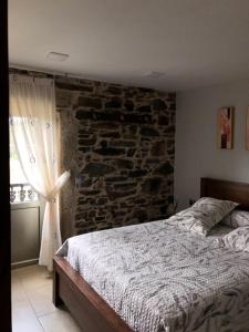 um quarto com uma cama e uma parede de pedra em Casa do Grallo em Corcoesto