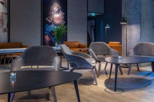 una sala d'attesa con tavoli, sedie e un quadro di Radisson Blu Hotel Frankfurt a Francoforte sul Meno