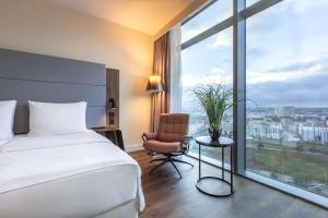 a hotel room with a bed and a chair and a window at Radisson Blu Hotel Frankfurt in Frankfurt