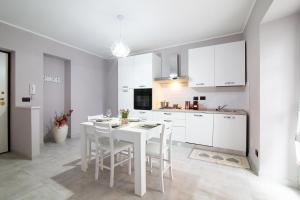 uma cozinha branca com uma mesa e cadeiras brancas em Claretta em Giaveno