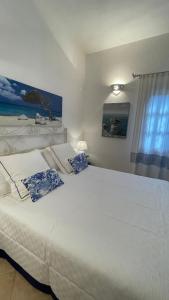 una camera da letto con un grande letto bianco con cuscini blu di Villa Margherita a Santa Margherita di Pula