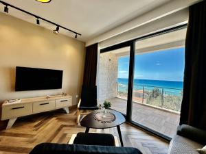 Sala de estar con TV y vistas al océano en White Star Apartments, en Utjeha