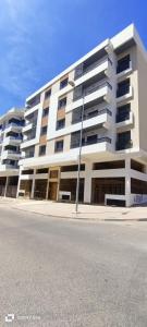 un grande edificio bianco sul lato di una strada di Victoria Mohammed V-Apartment a Bouskoura
