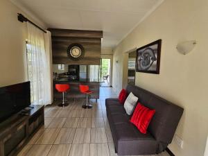 a living room with a brown couch and red pillows at Emlanjeni Guest Lodge in White River