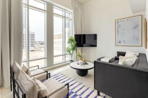 a living room with a couch and chairs and a tv at Frank Porter - The Lofts Central in Dubai