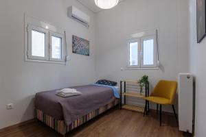 1 dormitorio pequeño con 1 cama y 1 silla amarilla en THE BEST HOUSE IN P.FALIRO NEAR THE SEA vipgreece, en Atenas