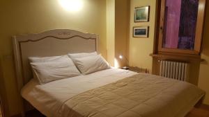Una cama con sábanas blancas y almohadas en un dormitorio en Appartement in Gavardo mit Pool, Garten und Grill, en Gavardo