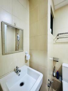 een badkamer met een witte wastafel en een spiegel bij ITCC Manhattan Suites by AURORA in Penampang