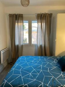 um quarto com uma cama azul e uma janela em T2 avec grand jardin,plage à pieds quartier des Lônes em Six-Fours-les-Plages