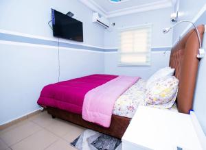 sypialnia z łóżkiem i telewizorem na ścianie w obiekcie NK HOME w mieście Nsimalen